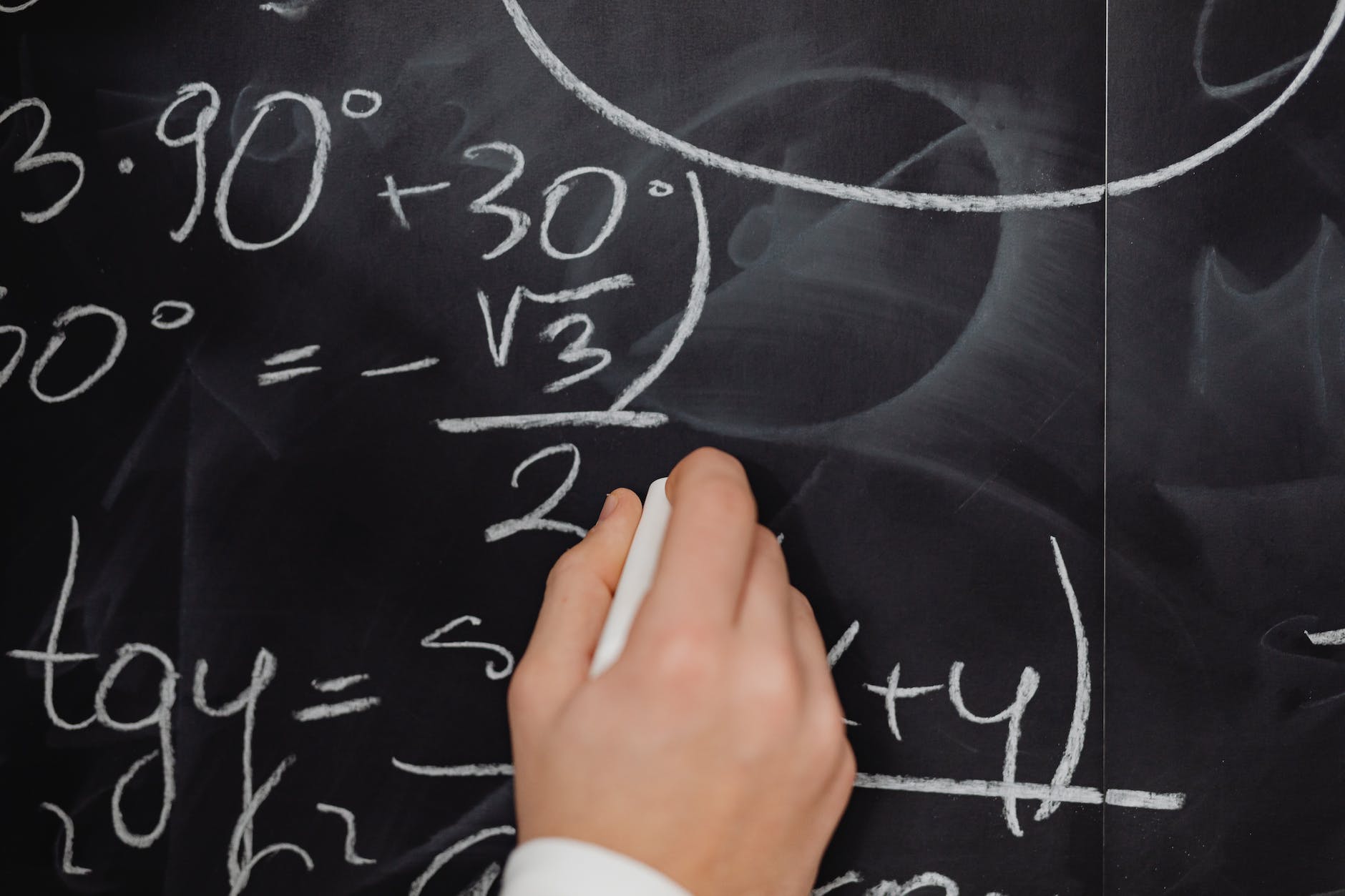 Hand writing math formula on blackboard