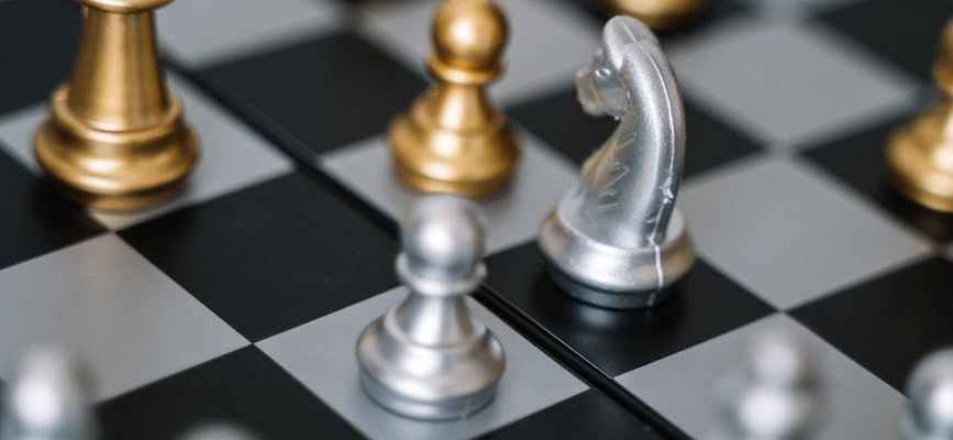 Gold and silver chess pieces on chess board