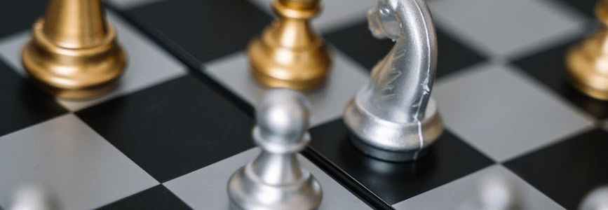 Gold and silver chess pieces on chess board