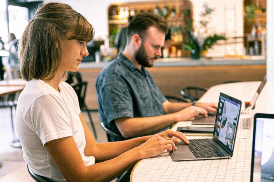 Photo of man and woman sitting down using laptops