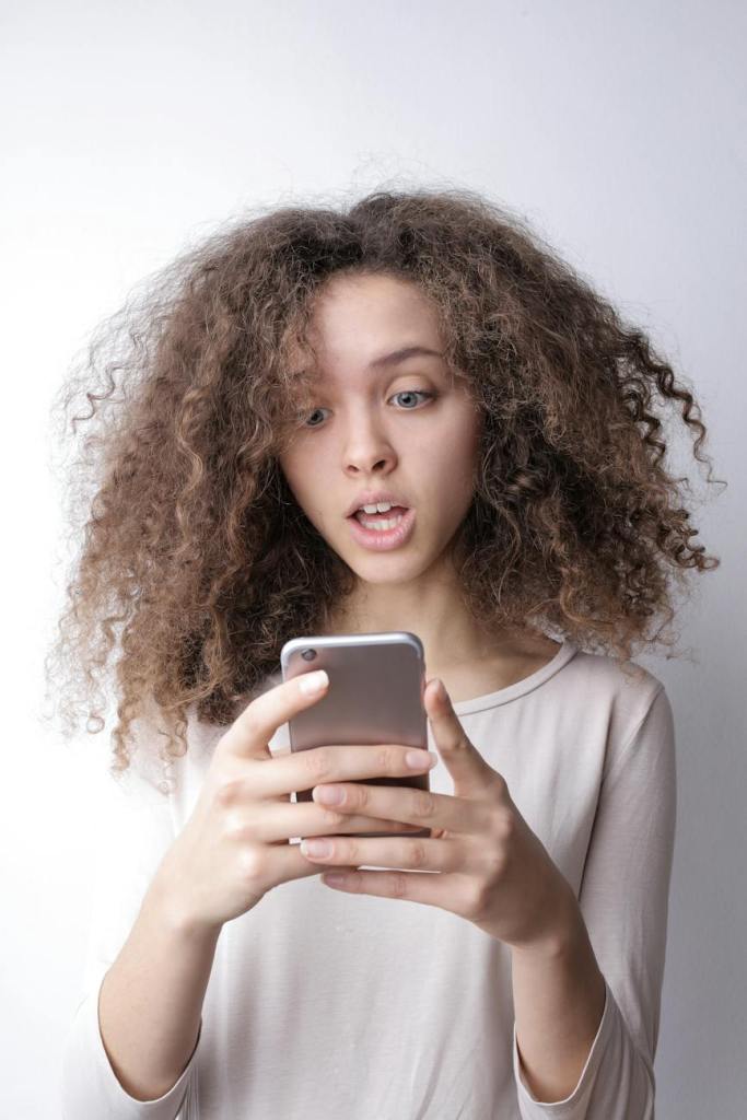 Young woman looking at mobile phone with surprised expression